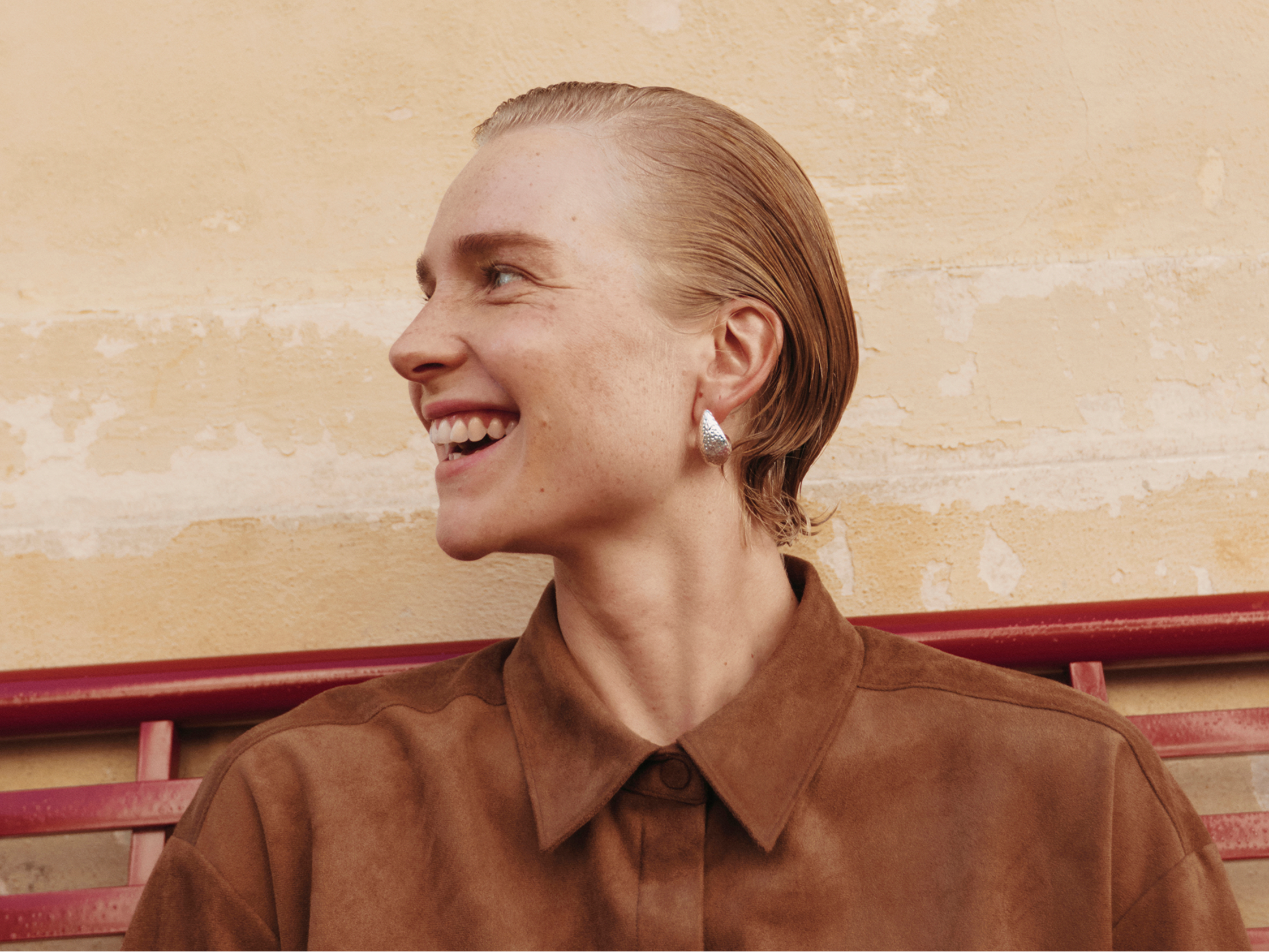 Smiling woman in brown shirt with blonde hair in profile view