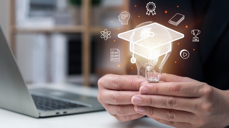 person holding lightbulb with icons surrounding lightbulb and laptop in background